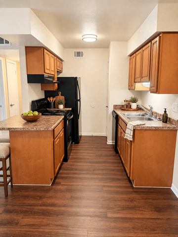 The Woodlands apartment for rent - A kitchen with wooden cabinets and a black refrigerator.