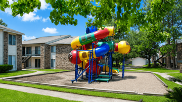 The Woodlands apartment for rent - A colorful playground structure with a slide in the middle of a grassy area.