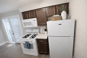 Kansas City apartment for rent - A white refrigerator stands in a kitchen with wooden cabinets and a white stove.