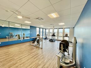 Denver apartment for rent - a gym with cardio machines and weights on a wooden floor