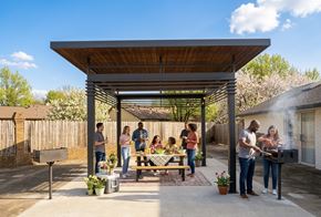 Rogers apartment for rent - A group of people are gathered around a picnic table under a wooden pergola.