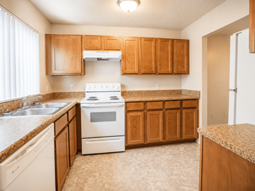 Broken Arrow townhouse for rent - A kitchen with a white stove and wooden cabinets.