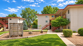 Lakewood apartment for rent - A playground with a slide and a wooden structure is in front of a building.