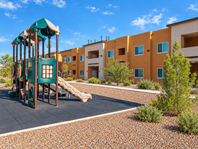 El Paso apartment for rent - A playground with a green slide and a brown and yellow building in the background.