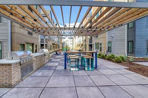 Aurora apartment for rent - A long covered walkway with benches and a brick wall on one side.