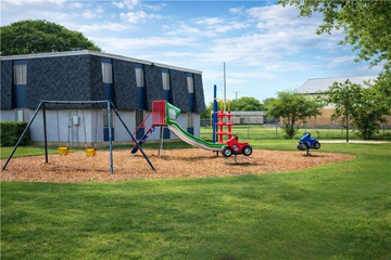 San Antonio apartment for rent - A playground with a red slide and a green slide in front of a building.