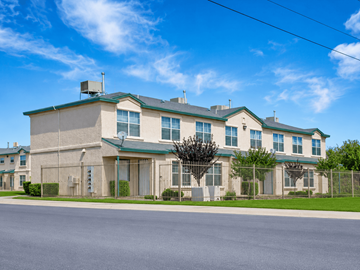 Socorro apartment for rent - A large, beige building with green roofs and a fence in front.