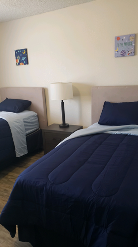 El Paso apartment for rent - A bed with a blue comforter and a white lamp on a nightstand.