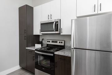St. Louis apartment for rent - A modern kitchen with a stainless steel refrigerator, microwave, and oven.