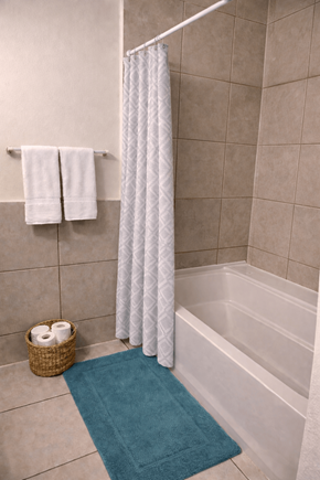 Denver apartment for rent - A white shower curtain hangs over a white bathtub in a bathroom.