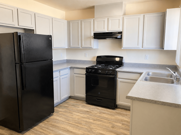 El Paso apartment for rent - A black refrigerator stands in a kitchen with white cabinets.