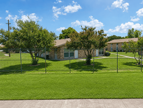 Shreveport apartment for rent - A grassy area with a building in the background and a fence in the foreground.