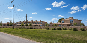 Clint apartment for rent - A row of houses with a stone wall in front.