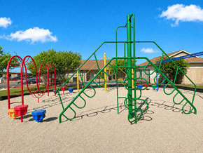 Kerrville apartment for rent - A playground with a green climbing frame and red and yellow swings.