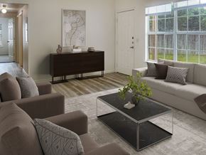 Kerrville apartment for rent - A living room with a brown sofa, a grey armchair, a black coffee table, and a white door.