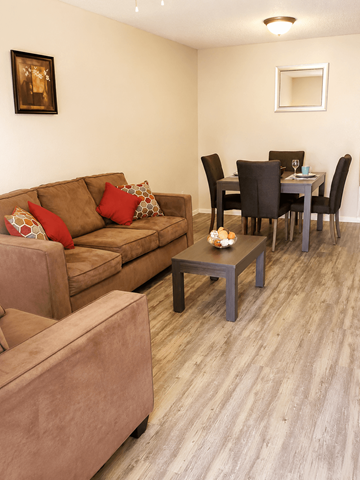 El Paso apartment for rent - A brown couch with red pillows sits in a living room with a dining table and chairs.
