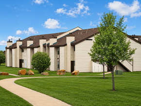 Tulsa apartment for rent - A tree stands in front of a building with a walkway in front of it.