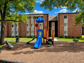 Rockford apartment for rent - A playground with a blue slide and a yellow slide in front of a brick building.