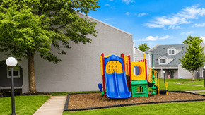 Lexington townhouse for rent - A playground with a slide and a climbing frame is in front of a grey building.