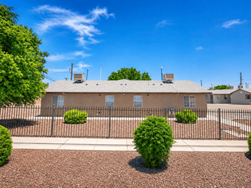 El Paso apartment for rent - A building with a black fence and bushes in front.