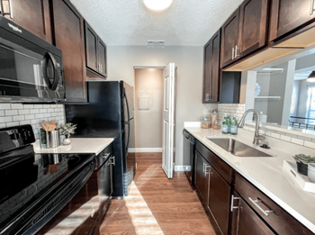 A kitchen with black appliances and wooden cabinets