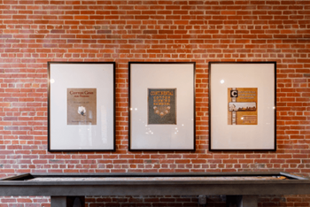 Three pictures hanging on a brick wall