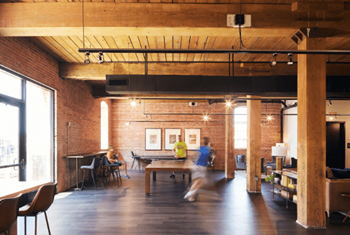 A large room with a ping pong table and people in it