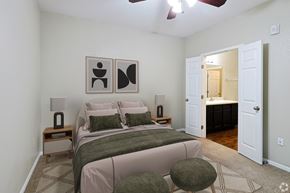 Bastrop townhouse for rent - A bedroom with a bed, two lamps, and two framed pictures on the wall.