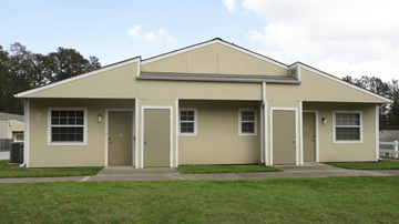 Little Rock apartment for rent - A beige building with a darker beige roof and a white fence in front.