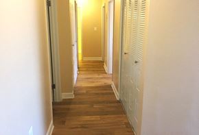 Baltimore apartment for rent - A long hallway with white walls and wood floors.