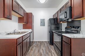 Boerne apartment for rent - A kitchen with dark wood cabinets and black appliances.