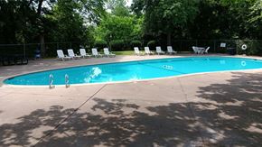 Broken Arrow townhouse for rent - a swimming pool with chaise lounge chairs and trees in the background