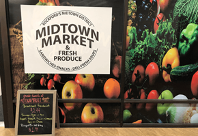 Rockford apartment for rent - A sign for Midtown Market is displayed in front of a wall of vegetables.