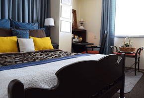 Rockford apartment for rent - A bedroom with a large bed and a nightstand with a lamp.