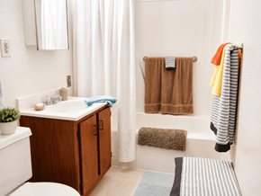 Rockford apartment for rent - A bathroom with a white tub, a wooden cabinet, and a striped towel hanging on the rack.