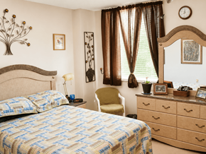 Rockford apartment for rent - A bedroom with a bed, chair, and a clock on the wall.