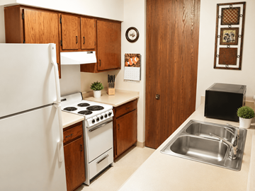 Rockford apartment for rent - A kitchen with a white refrigerator, wooden cabinets, a stove, and a sink.