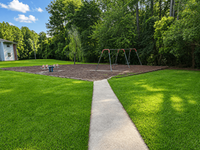 Waycross apartment for rent - A playground with a swing set in the middle of a grassy area.