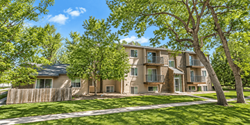 Denver apartment for rent - A large apartment complex with a fence and trees in front.