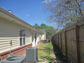 Lumberton apartment for rent - the side of a house with a yard and a wooden fence