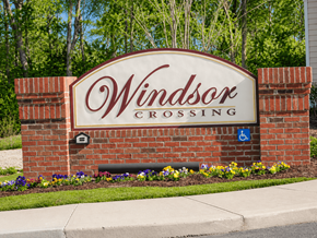 Lumberton apartment for rent - A sign for Windsor Crossing with a brick wall and flowers.