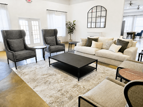 Conroe apartment for rent - A living room with a grey sofa, two grey armchairs, a black coffee table, and a rug.