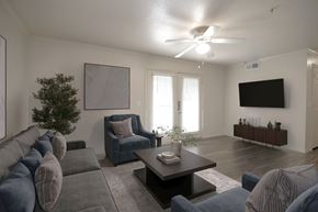 Austin apartment for rent - A living room with a grey couch, a blue chair, a coffee table, and a flat screen TV mounted on the wall.