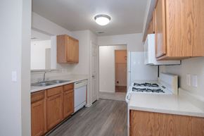 Austin apartment for rent - an empty kitchen with wooden cabinets and white appliances and a stove top oven