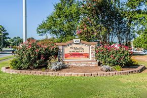 North Little Rock apartment for rent - A sign for "The Bluffs" on Main Street is surrounded by greenery and flowers.