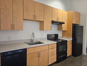 Memphis apartment for rent - A kitchen with black appliances and wooden cabinets.at South Main Artspace Lofts, Memphis, TN 38126