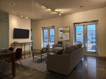Memphis apartment for rent - A living room with a grey couch, a wooden dining table with chairs, a flat screen TV, and a coffee table with a plant on it.