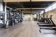 Prattville apartment for rent - a gym with weights and cardio machines and a brick wall at The Mill at Prattville, Prattville, AL
