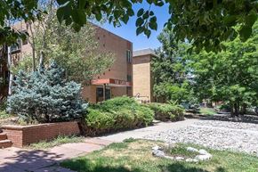 Denver apartment for rent - A building with a sign that says "The Canyon" is surrounded by trees and bushes.