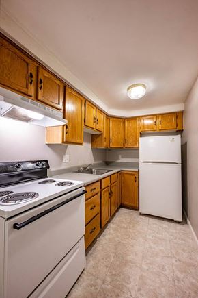 Lowell apartment for rent - a kitchen with white appliances and wooden cabinets